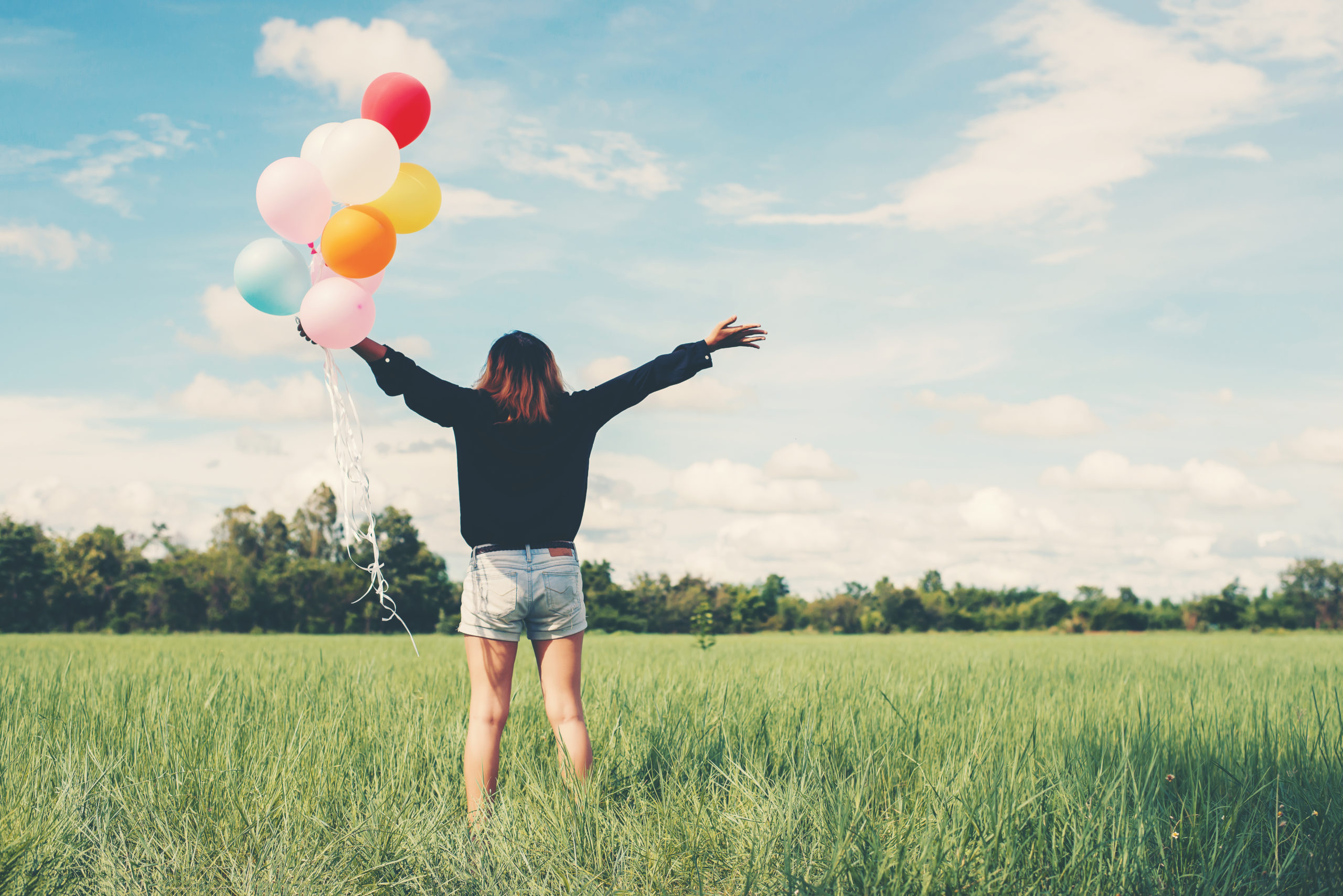 femme avec des ballons de couleur illustrant le bonheur le bien-être la joie psychologue psychothérapie cognitive et comportementale tcc thérapie assistée par l'animal zoothérapie écopsychologie